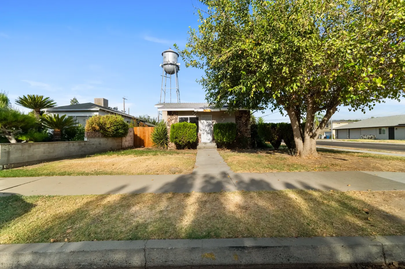 Single storey home seen from the street, with a water tower rising behind it.
